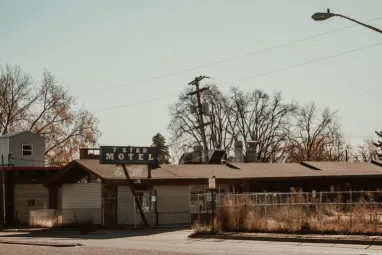 A vintage 7 Star Motel with a prominent sign, surrounded by tall grass and fencing, under a clear sky.