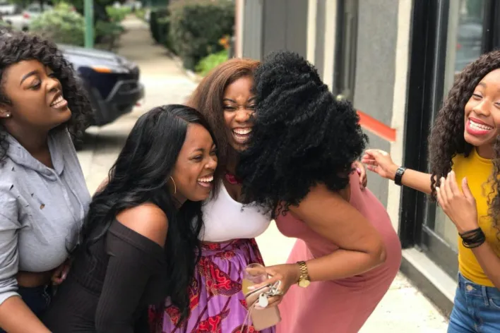 A joyful group of friends sharing a moment of laughter on a sunny day outdoors.