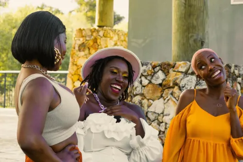 Three women laughing together outdoors, showcasing joy and friendship.