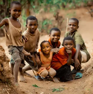 Group of smiling children posing together in a rural setting in Bujumbura, Burundi.