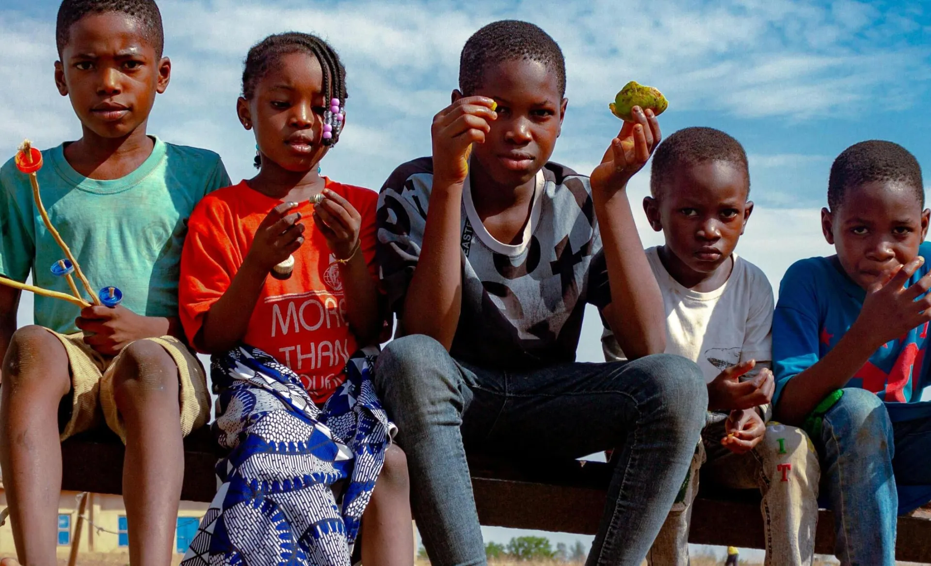 A group of children having fun outdoors in Kaduna, Nigeria, enjoying playtime under a bright sky.
