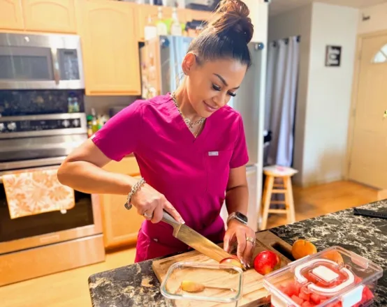 Woman arranging fresh vegetables and pasta on plates in a kitchen setting.