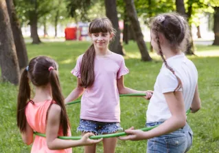 Back view of a young girl playing with a hula hoop in a sunny garden.