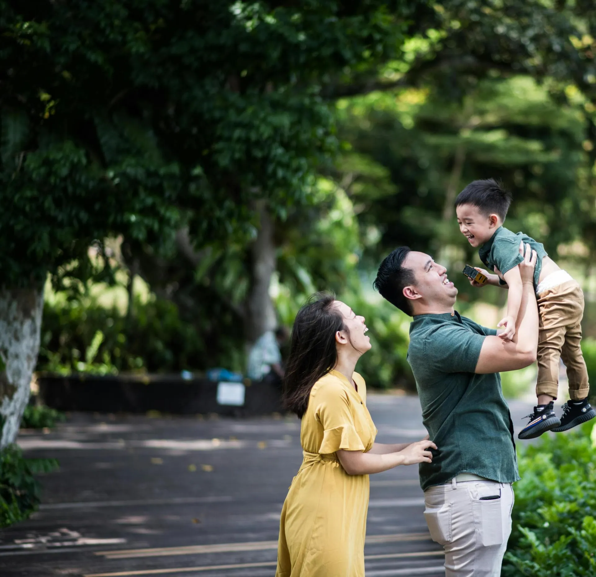 Joyful family bonding moment in a lush Singapore park setting, capturing laughter and love.