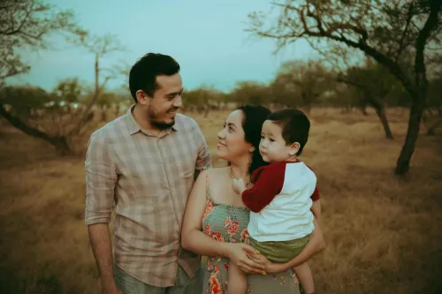 Family portrait of parents with child in warm outdoors setting, capturing joyful moments together.