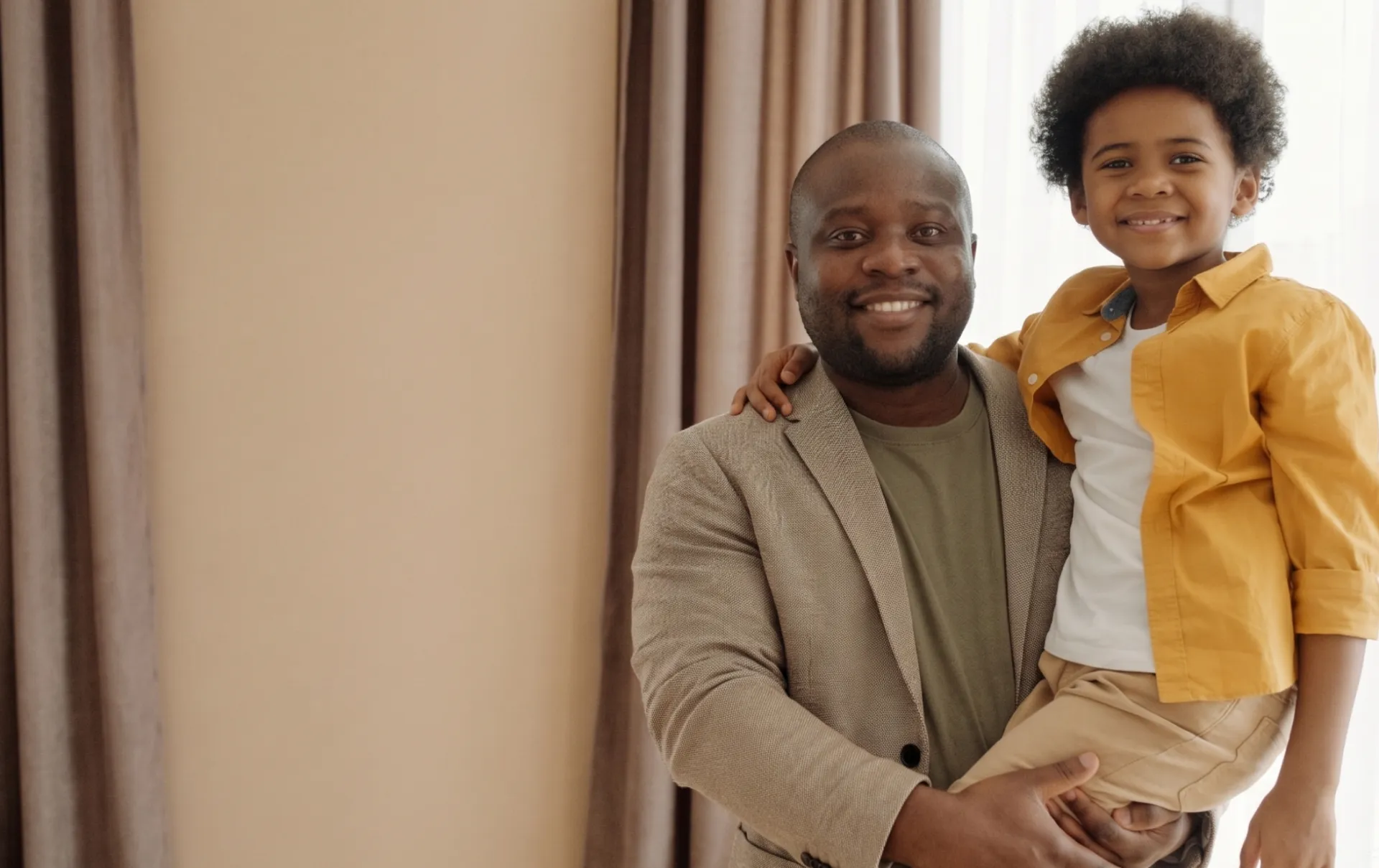 Joyful father and son smiling together indoors, showcasing family happiness.