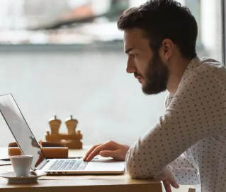 Elderly man focused on his laptop in a stylish, colorful office environment.