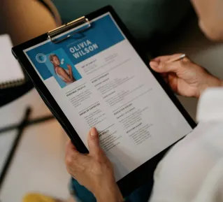 An HR professional reviews a resume on a clipboard during an office meeting.