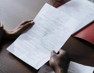 Adults reviewing legal documents on a wooden desk indoors, highlighting professional collaboration.