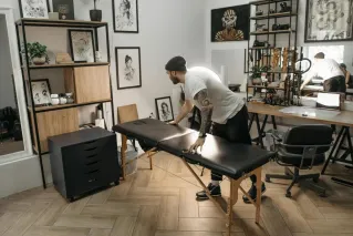 Tattoo artist arranging work table in a stylish studio with art decor and cozy setup.
