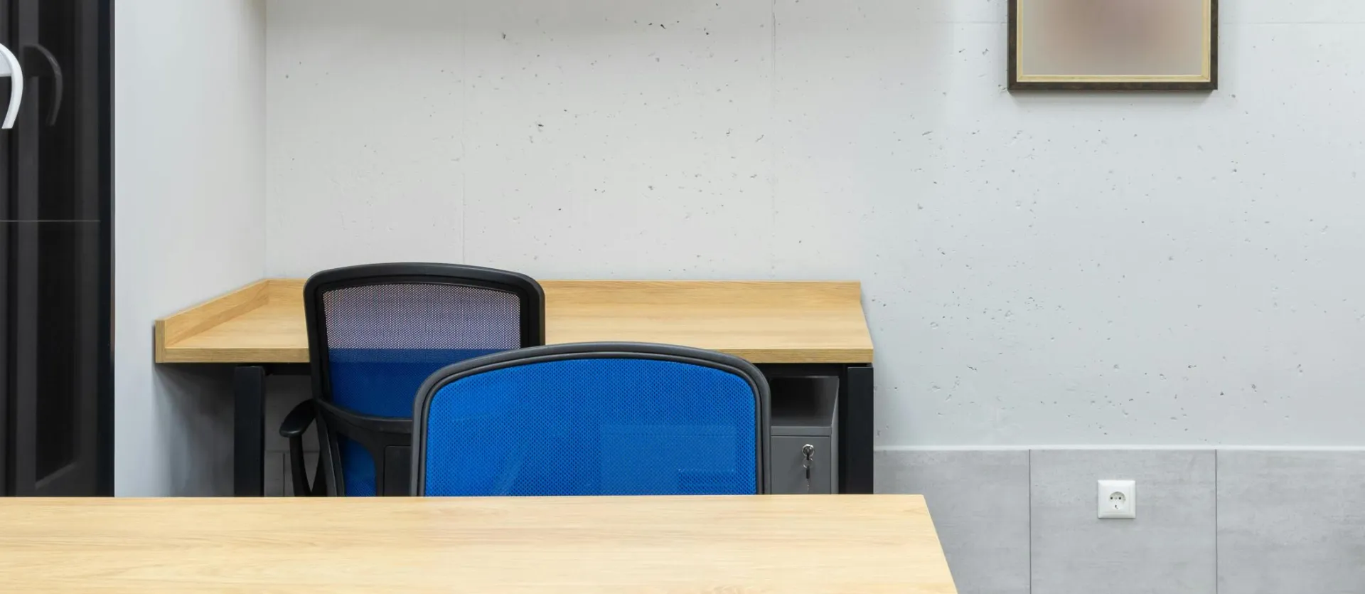Wooden tables and blue office chairs placed in modern workplace with shelves on wall