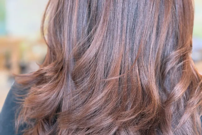 Hairdresser applying dye to client's hair with precision, showcasing modern salon hair coloring techniques.