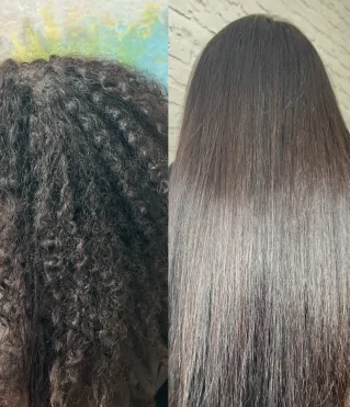 A stylist blow-dries a woman's hair using a brush and hairdryer in a salon.