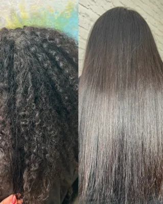 A stylist blow-dries a woman's hair using a brush and hairdryer in a salon.