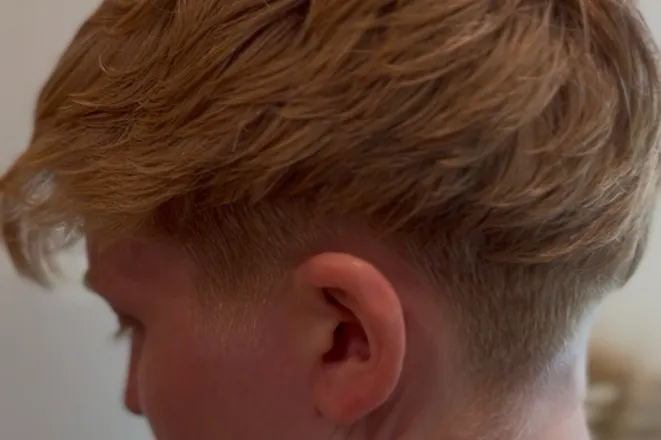 Professional hair stylist with scissors and comb, ready for a haircut.