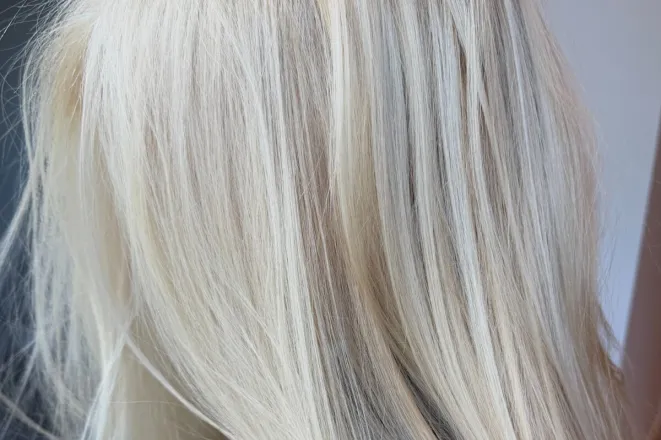 A hairdresser applies dye in a salon, capturing a professional hair treatment in stylish black and white.