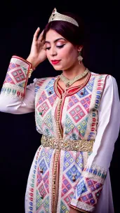 Woman in vibrant Moroccan caftan with intricate patterns and jewelry.