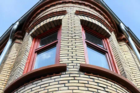 Detailed view of a brick building facade with red-framed arched windows.