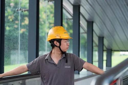 Construction worker in a hard hat examines an industrial site, showcasing safety and industry.
