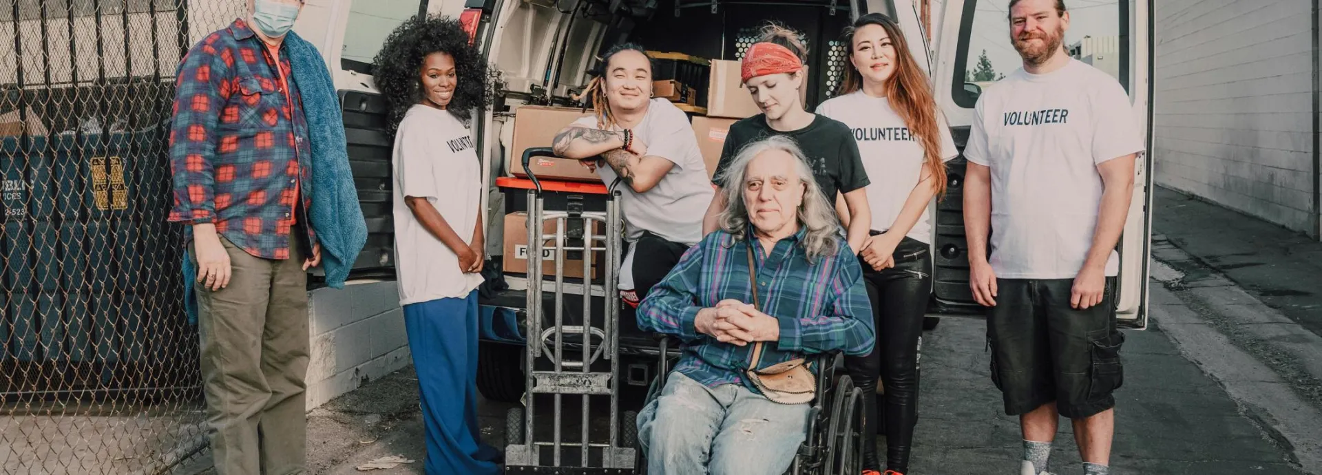 A diverse group of volunteers unloading a van for a charity event, showcasing teamwork and support.