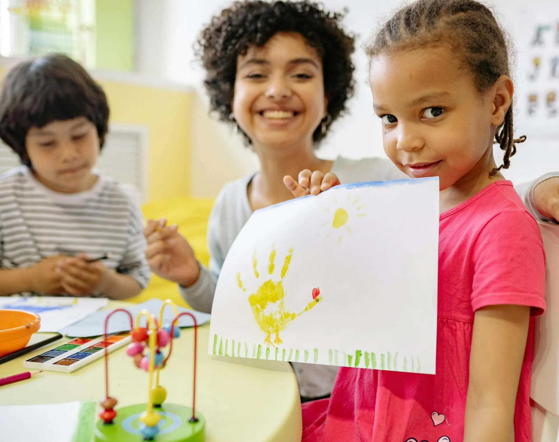 Kids enjoying creative painting activities with teacher in a cheerful classroom setting.