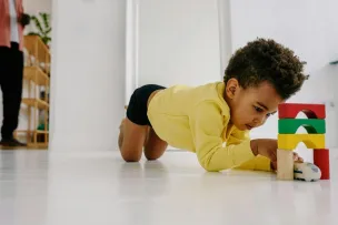 Young child engaged with toy blocks in a bright home setting, expressing creativity and fun.