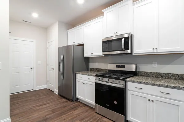 Contemporary kitchen featuring stainless steel fridge and microwave with white cabinetry.