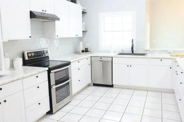 A bright and spacious modern kitchen with white cabinets, appliances, and natural light.
