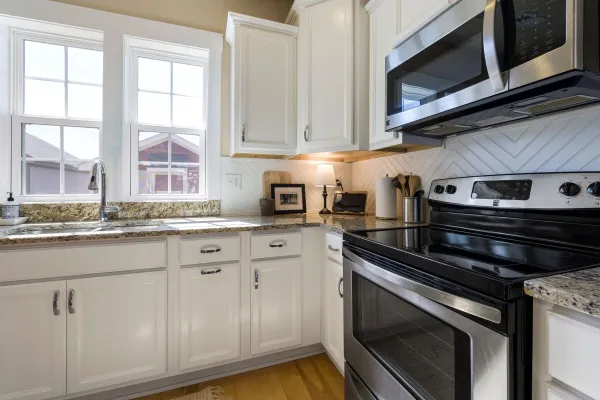 Bright and stylish modern kitchen featuring white cabinets and granite countertops with stainless steel appliances.
