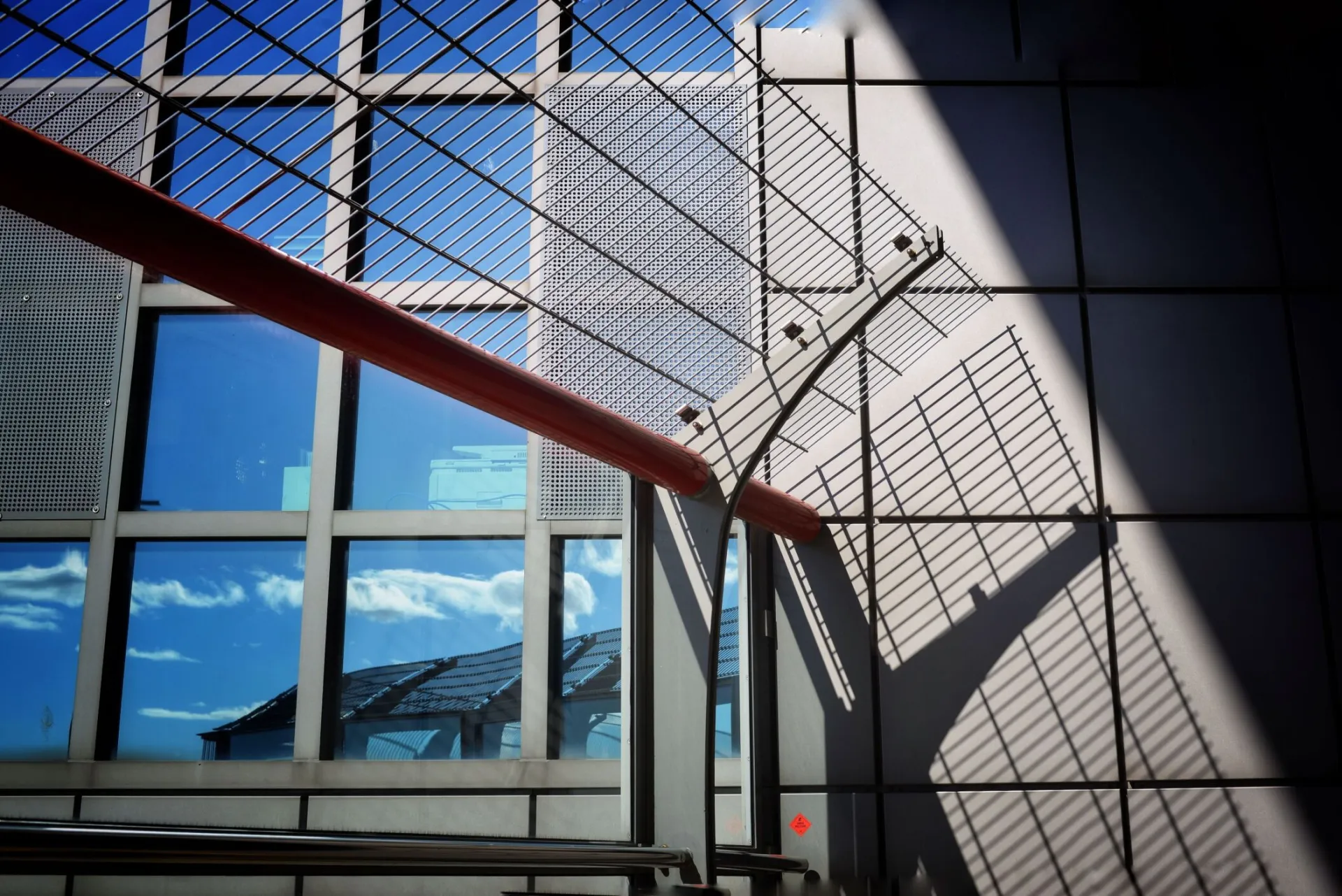 Sunlit modern architecture with shadows and reflections on windows.
