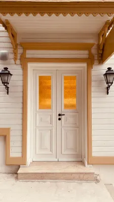 Front view of a classic wooden door with decorative yellow glass panes and wall lamps.