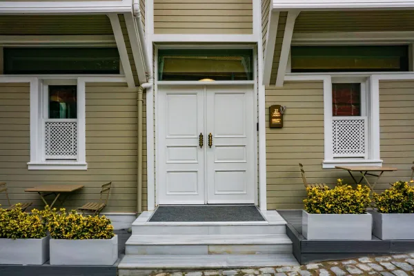 Charming entrance of a house featuring white double doors and outdoor seating.