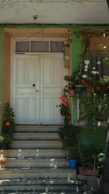 Vertical shot of a house entrance with white doors and colorful potted flowers, creating a welcoming atmosphere.
