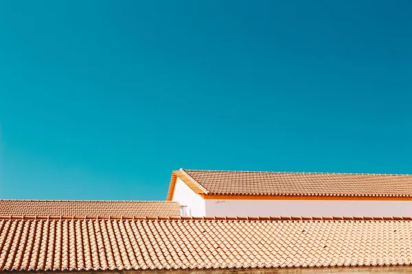 A serene image of terracotta roofs contrasting with a vibrant blue sky, showcasing architectural simplicity.