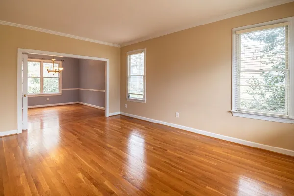 Bright empty room with wooden floors and large windows, ideal for real estate listings.