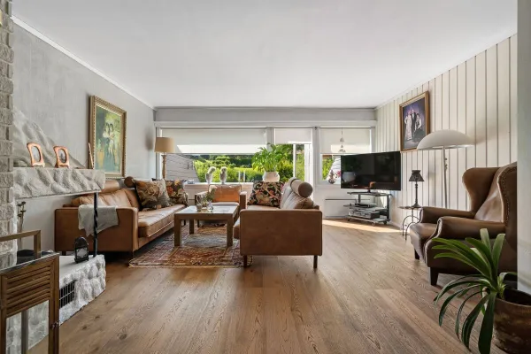 Spacious living room with modern decor, leather sofas, and natural lighting.