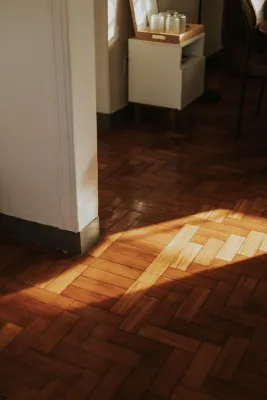 Warm sunlight cast on wooden parquet flooring in a cozy indoor setting.