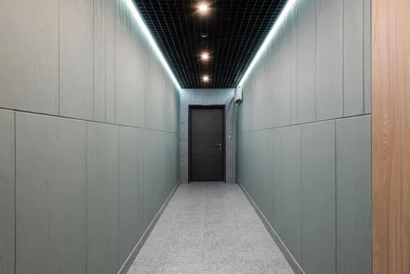 Perspective view of empty hallway with entrance door and illuminated ceiling in contemporary workplace