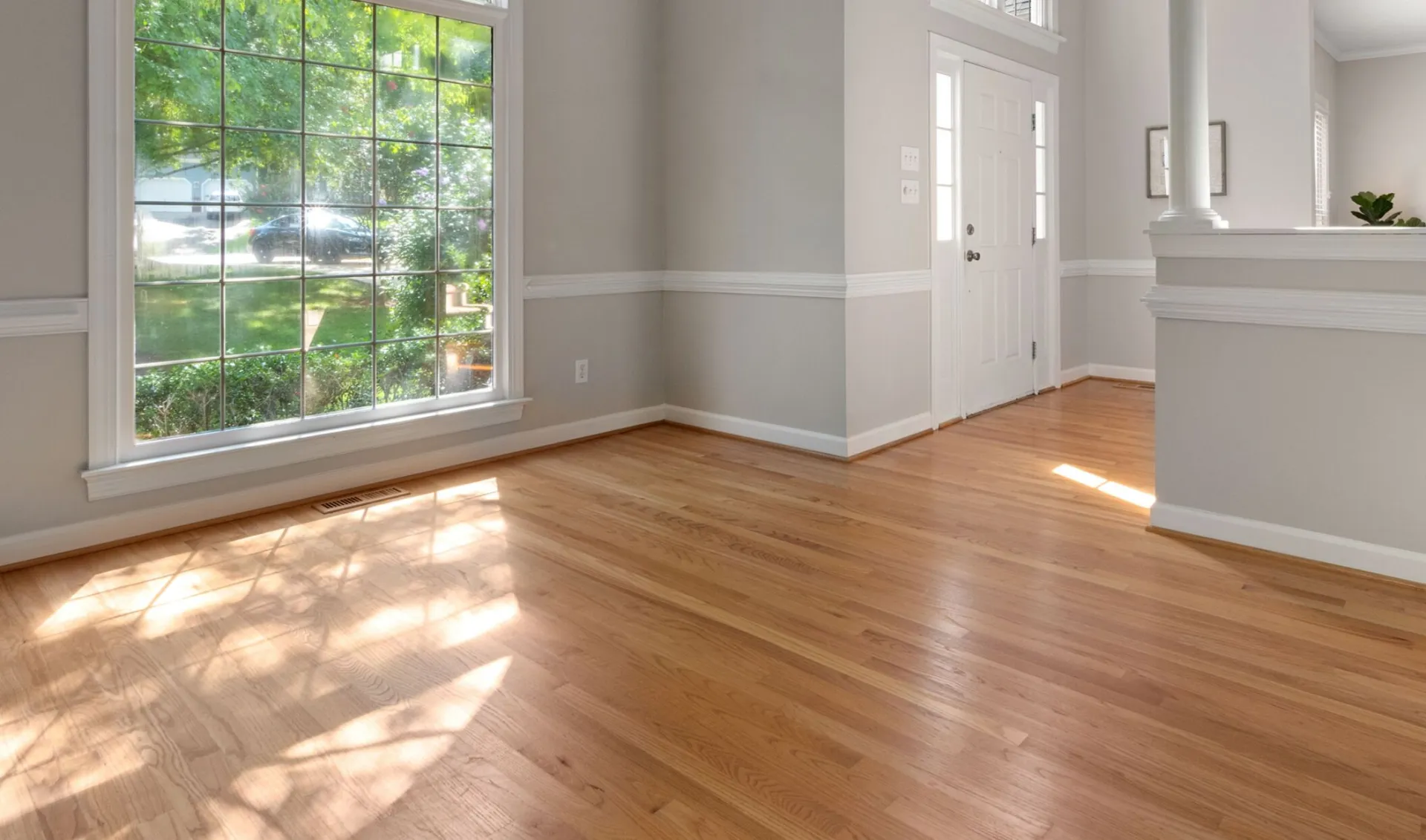 Bright living room with large window and hardwood floors, perfect for residential spaces.