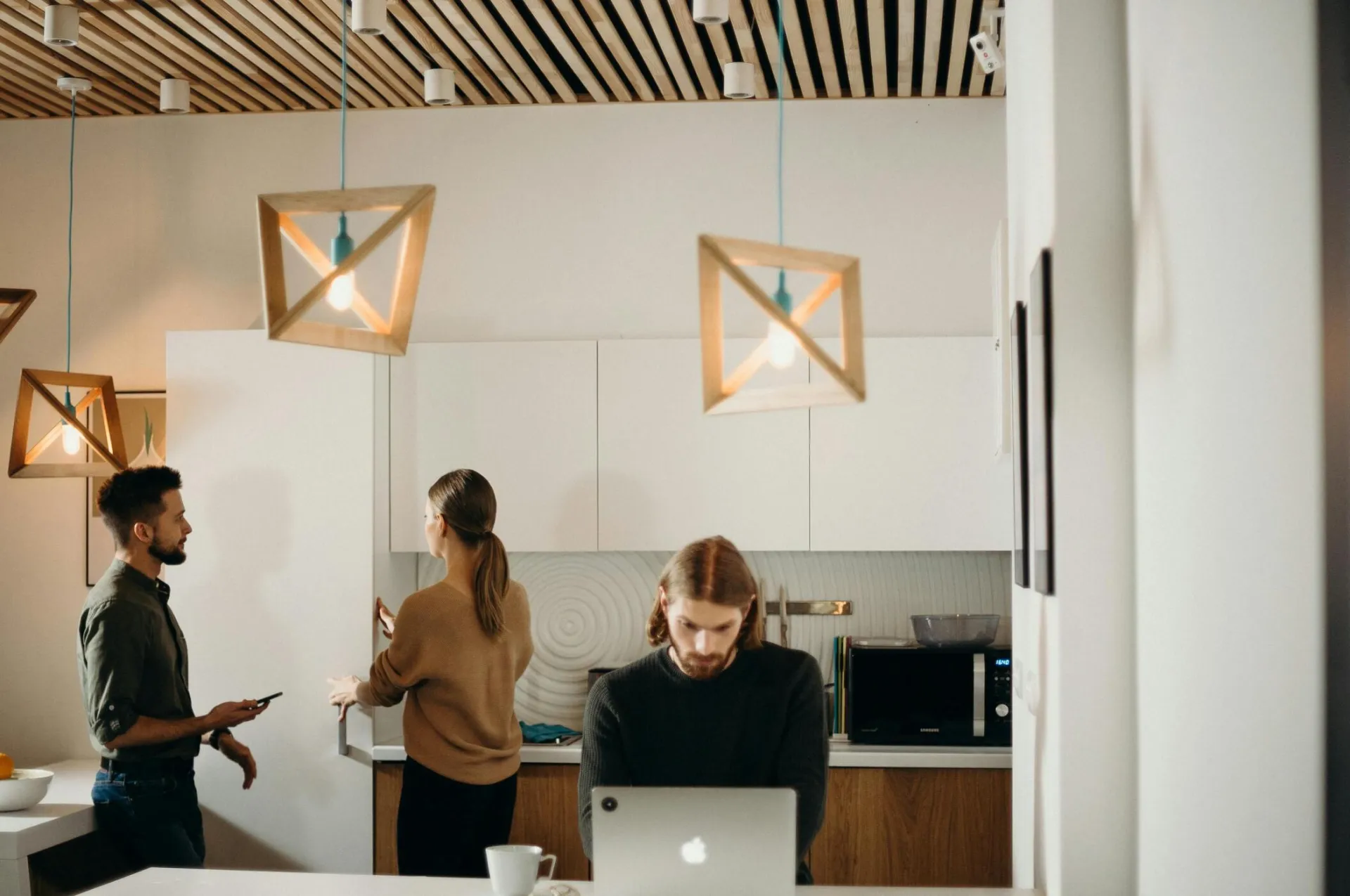 Three professionals working together in a chic, modern office kitchen.