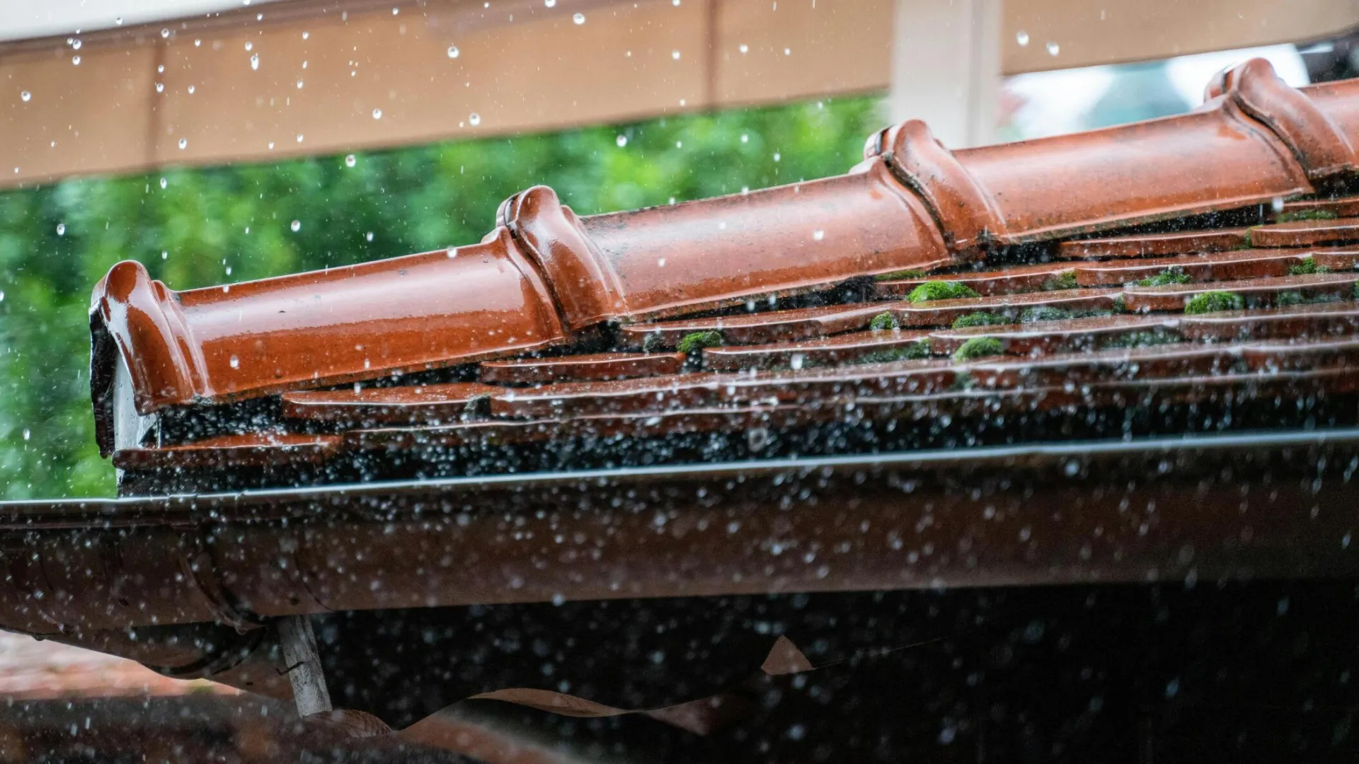 Detailed view of rain droplets cascading off a terracotta roof, capturing the essence of a rainy day.