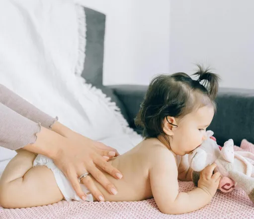 A serene moment of a baby receiving a gentle massage while holding a plush toy, epitomizing peace and comfort.