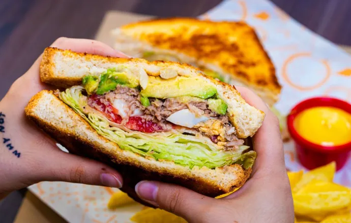 Delicious veggie sandwich with avocado and chips, perfect for lunch or snack.