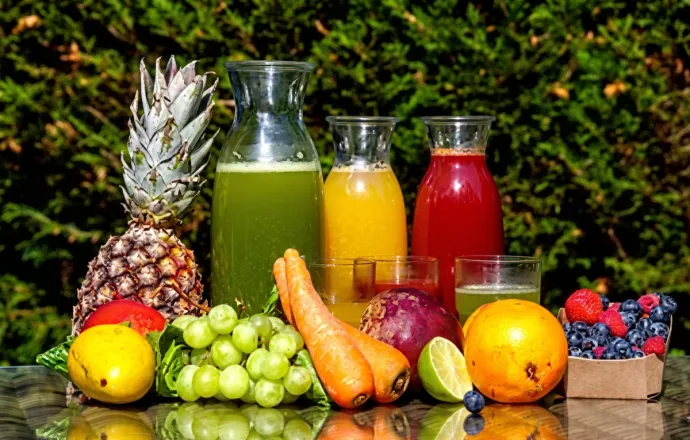 A vibrant display of fresh fruit juices in the sunlight with various garnishes.