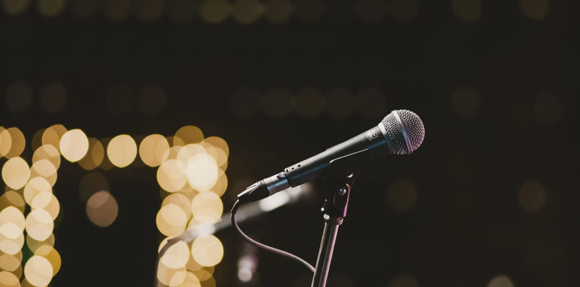 Microphone on stand with bokeh lights in the background, perfect for music themes.