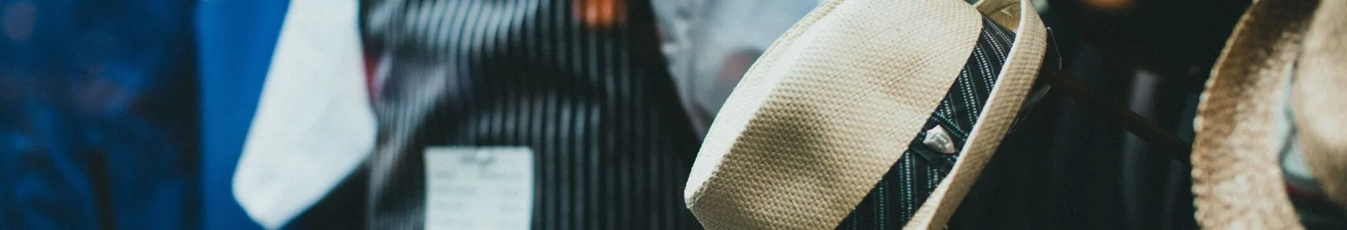 Close-up of fashionable fedora hats and aprons in a stylish boutique window display.
