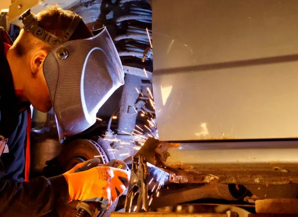 A skilled welder wearing protective gear working on metal with sparks flying in an industrial setting.