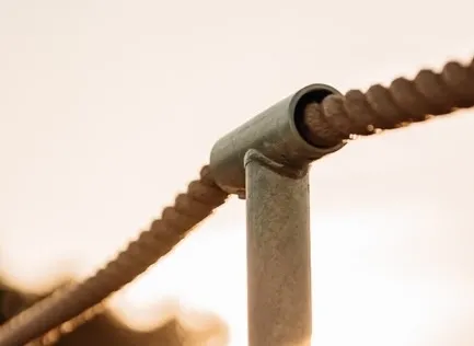 A worker welds metal beams outdoors, showcasing industrial craftsmanship and safety gear.