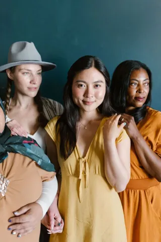 A diverse group of women posing against a dark background, showcasing unity and strength.