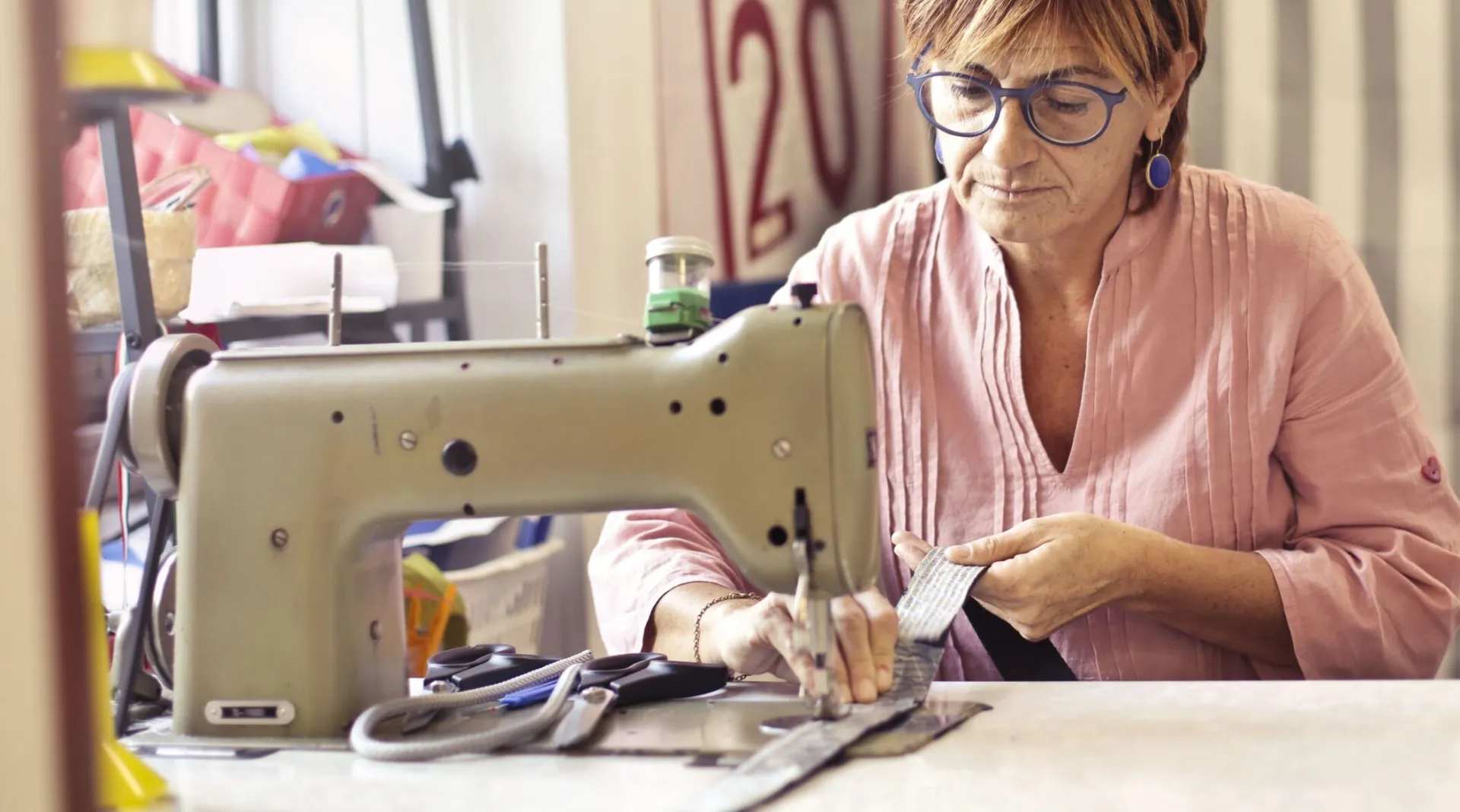 A woman intently working with a sewing machine in her workshop, showcasing craftsmanship.